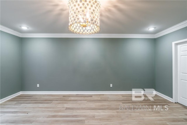 empty room featuring light hardwood / wood-style flooring, a chandelier, and ornamental molding