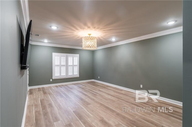 spare room featuring crown molding, light hardwood / wood-style flooring, and an inviting chandelier