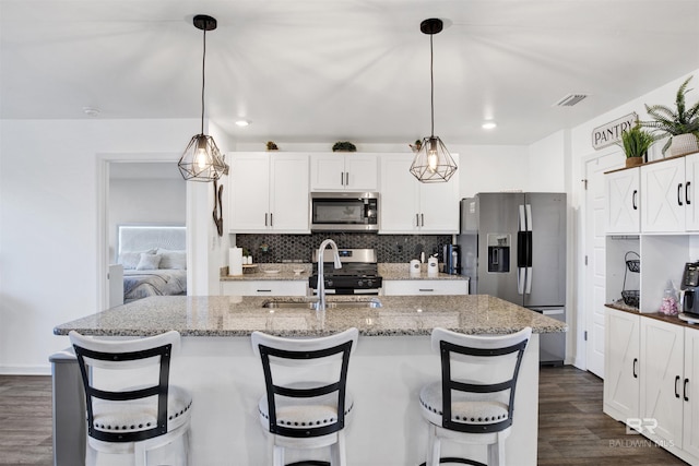 kitchen featuring backsplash, dark stone counters, hanging light fixtures, and appliances with stainless steel finishes