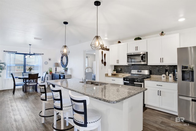 kitchen featuring pendant lighting, stainless steel appliances, tasteful backsplash, and an island with sink