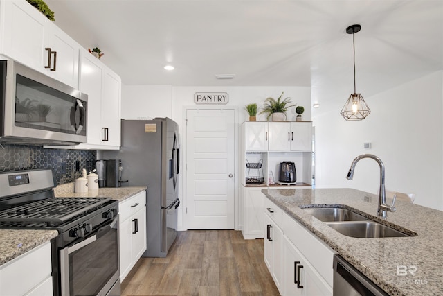 kitchen with sink, white cabinets, decorative light fixtures, and appliances with stainless steel finishes