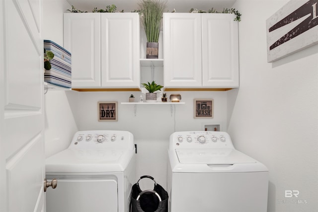 washroom with washer and dryer and cabinets