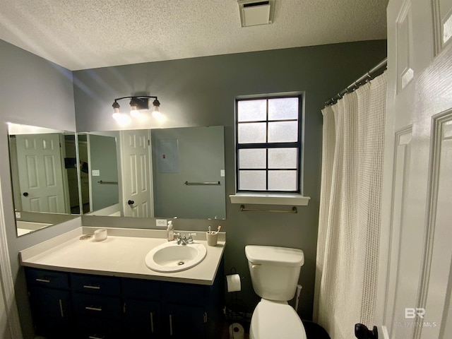 bathroom with a textured ceiling, vanity, and toilet