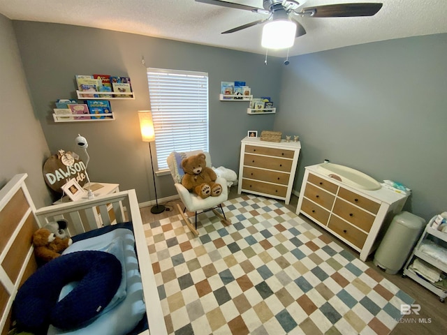 playroom with ceiling fan and a textured ceiling