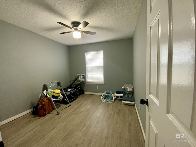 interior space featuring ceiling fan, wood-type flooring, and a textured ceiling