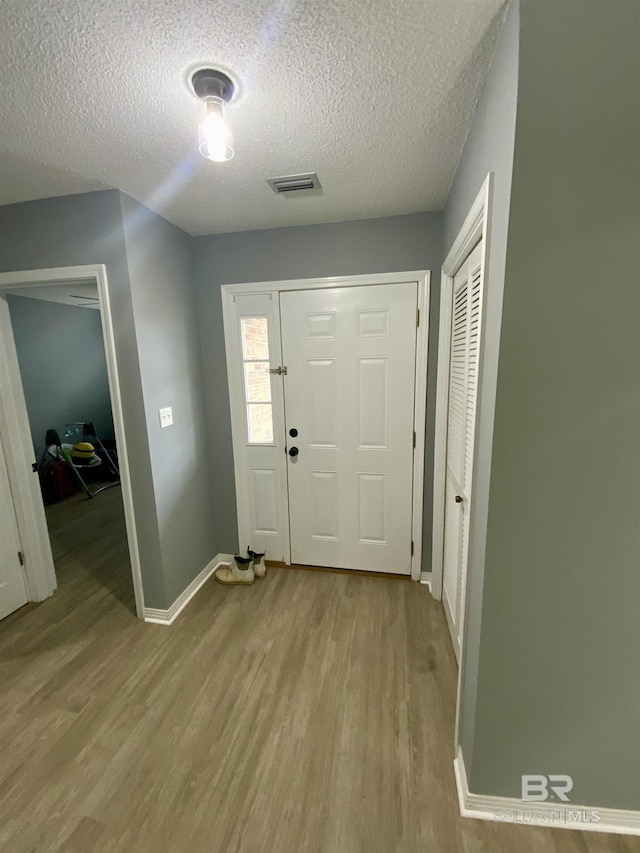 entryway with light hardwood / wood-style floors and a textured ceiling