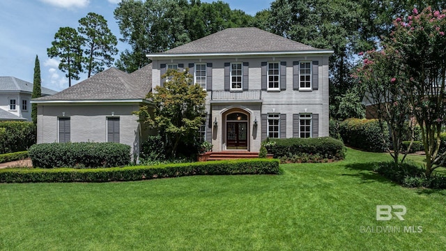 view of front facade featuring french doors, brick siding, a front lawn, and a shingled roof