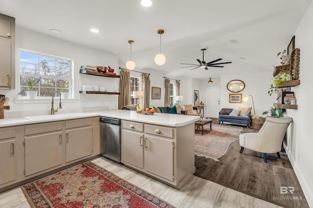 kitchen with sink, light hardwood / wood-style flooring, dishwasher, decorative light fixtures, and kitchen peninsula