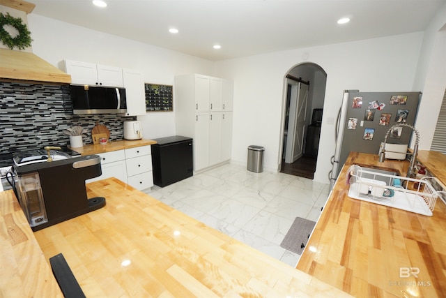 kitchen with wooden counters, decorative backsplash, white cabinetry, and sink