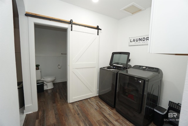 clothes washing area featuring a barn door, separate washer and dryer, and dark wood-type flooring