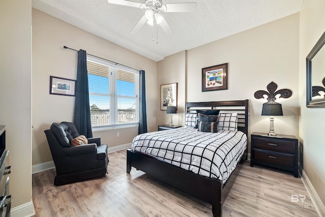 bedroom with ceiling fan, light hardwood / wood-style floors, and a textured ceiling