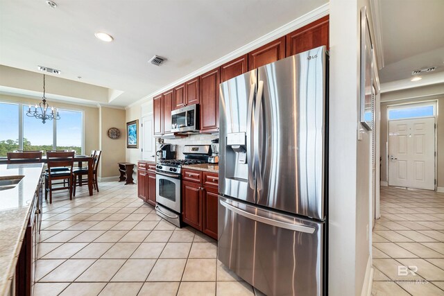 kitchen featuring hanging light fixtures, stainless steel appliances, light stone countertops, light tile patterned flooring, and a raised ceiling