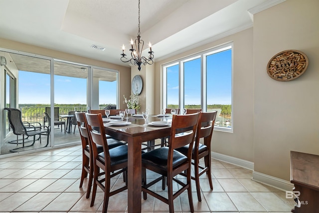 dining space with crown molding, light tile patterned floors, a chandelier, and a tray ceiling