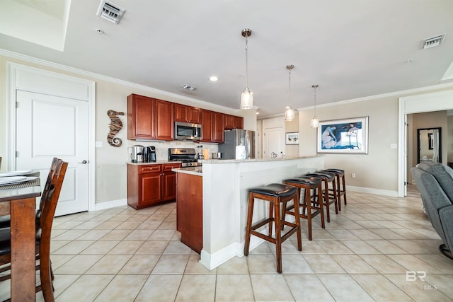 kitchen with hanging light fixtures, ornamental molding, light tile patterned flooring, and appliances with stainless steel finishes