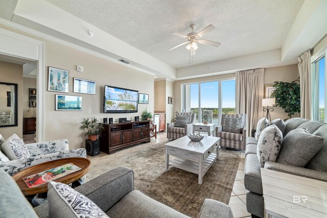 living room featuring light tile patterned floors, a tray ceiling, a textured ceiling, and ceiling fan