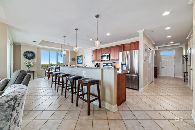 kitchen featuring appliances with stainless steel finishes, pendant lighting, a breakfast bar area, light tile patterned floors, and crown molding