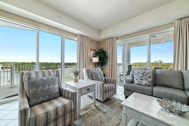 living room featuring a water view, a textured ceiling, and light tile patterned floors