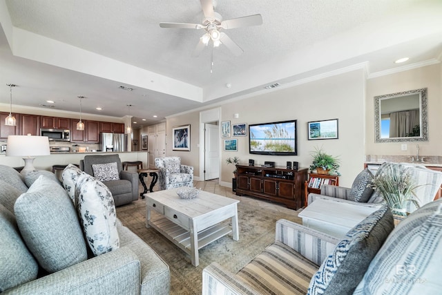 tiled living room with crown molding, ceiling fan, a raised ceiling, and a textured ceiling