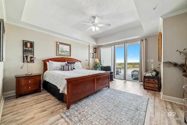 bedroom featuring a raised ceiling, a textured ceiling, light hardwood / wood-style flooring, and access to outside