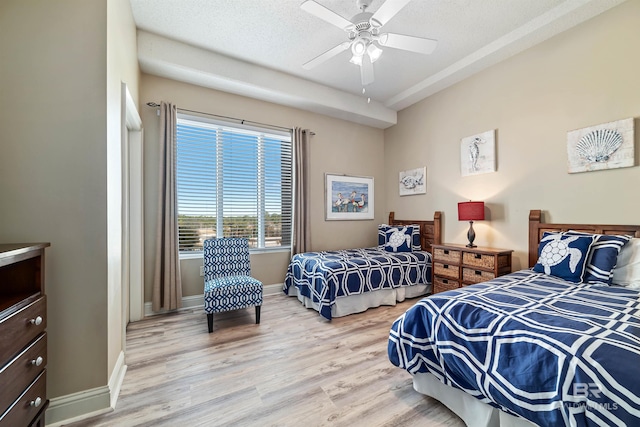 bedroom with ceiling fan, light hardwood / wood-style floors, and a textured ceiling