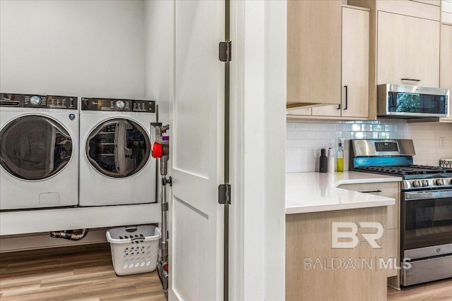 laundry area featuring washer and clothes dryer and light wood-style flooring