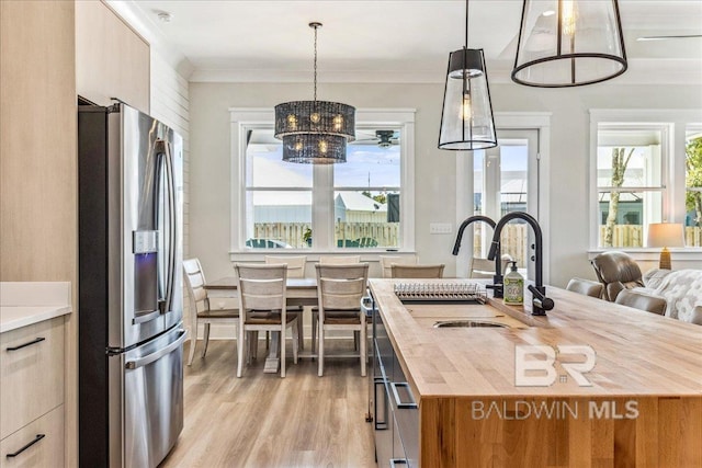 kitchen featuring crown molding, a wealth of natural light, wood counters, and stainless steel fridge