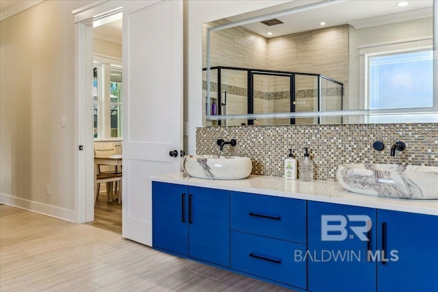 bathroom with tasteful backsplash, a shower stall, a sink, double vanity, and wood finished floors