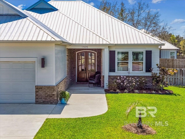 view of front of property with fence, an attached garage, brick siding, a front lawn, and french doors