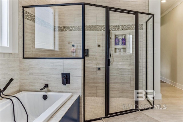 bathroom with a bath, ornamental molding, baseboards, and a stall shower