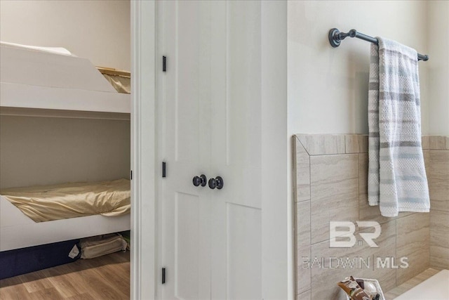 bathroom with wood finished floors and tiled shower