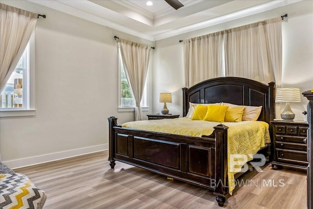 bedroom featuring baseboards, ornamental molding, wood finished floors, recessed lighting, and a raised ceiling
