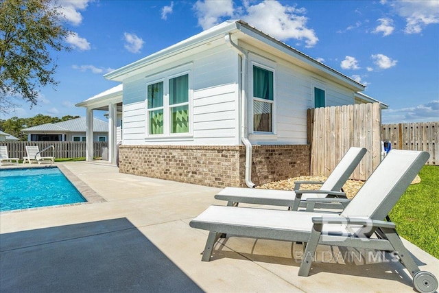 rear view of house featuring a patio, brick siding, fence, and a fenced in pool
