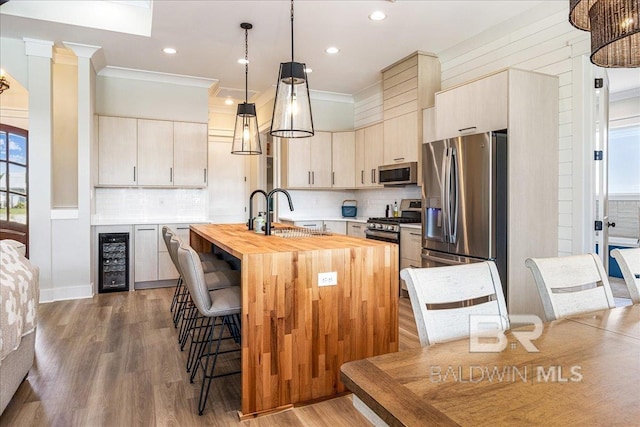 kitchen with stainless steel appliances, wine cooler, a breakfast bar, a sink, and butcher block counters