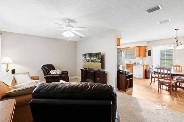 living room with light wood-type flooring, a textured ceiling, and ceiling fan with notable chandelier