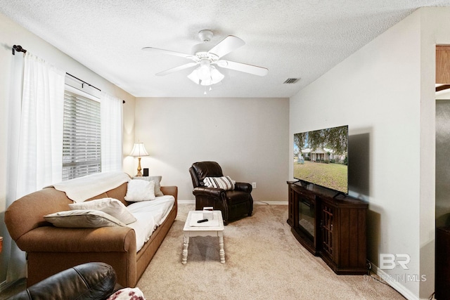 carpeted living room featuring ceiling fan and a textured ceiling