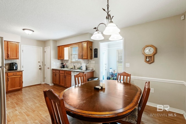 dining area with sink, a notable chandelier, and light wood-type flooring