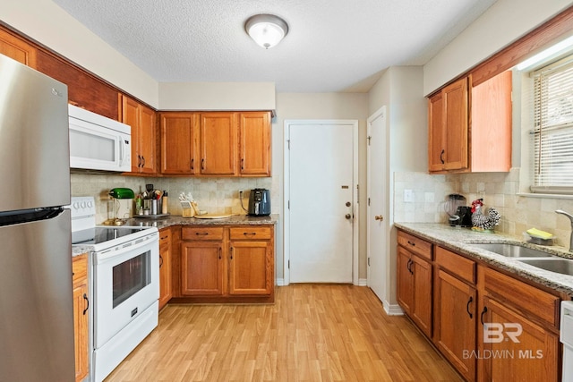 kitchen with a textured ceiling, tasteful backsplash, sink, and white appliances