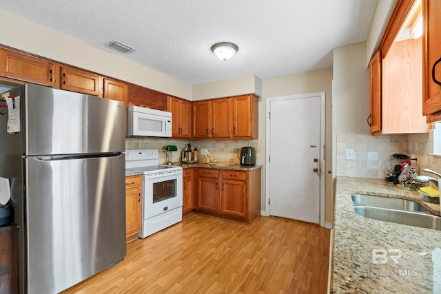 kitchen with tasteful backsplash, light stone counters, sink, and white appliances