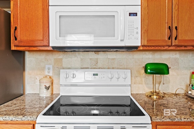 kitchen with decorative backsplash, light stone countertops, and white appliances