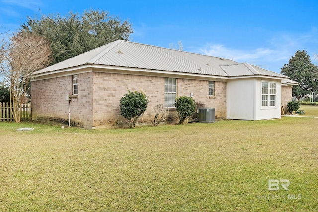 rear view of property featuring a lawn and cooling unit