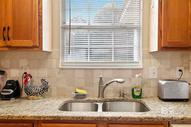 kitchen with light stone countertops, tasteful backsplash, and sink