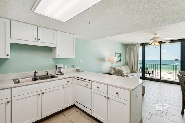 kitchen with dishwasher, white cabinets, a water view, sink, and kitchen peninsula