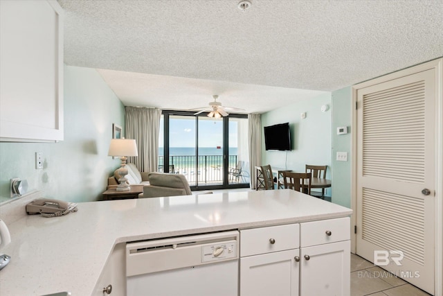 kitchen featuring white cabinets, white dishwasher, a textured ceiling, and expansive windows