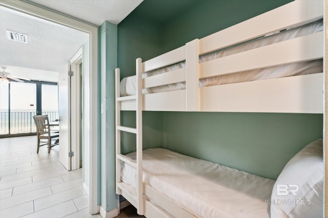 tiled bedroom featuring a textured ceiling and expansive windows