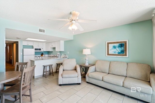 living room with ceiling fan and a textured ceiling