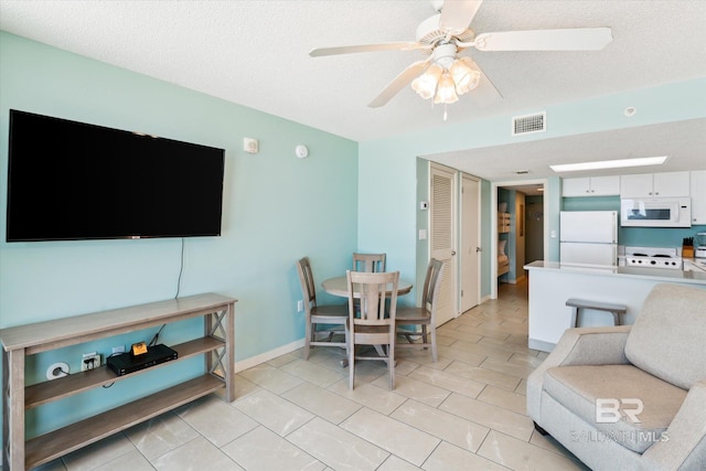 tiled dining room featuring ceiling fan and a textured ceiling