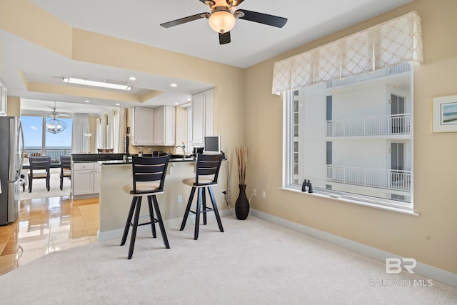 13621 Perdido Key Dr Unit 1804W, Perdido Key, FL 32507 - kitchen with white cabinetry, kitchen peninsula, a breakfast bar, stainless steel fridge, and light carpet