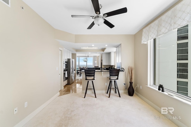 13621 Perdido Key Dr Unit 1804W, Perdido Key, FL 32507 - kitchen featuring white cabinetry, a kitchen breakfast bar, ceiling fan, stainless steel refrigerator, and light colored carpet