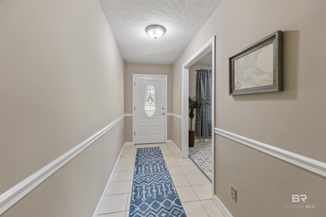 entryway with baseboards, light tile patterned flooring, and a textured ceiling