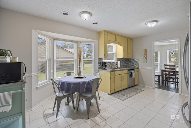 kitchen with appliances with stainless steel finishes, decorative backsplash, a healthy amount of sunlight, and a sink